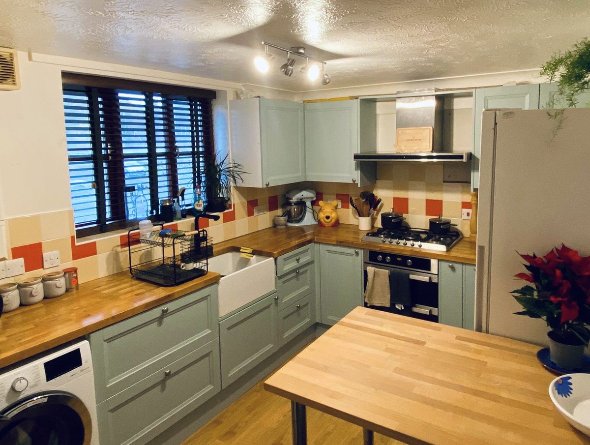 Kitchen after renovation with blue cabinets and wooden countertops